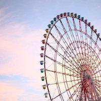ピンクやオレンジの夕焼け空にカラフルなゴンドラの大きな観覧車の写真