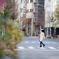 横断歩道を手を上げて渡る女性と牛のキャラクターの写真