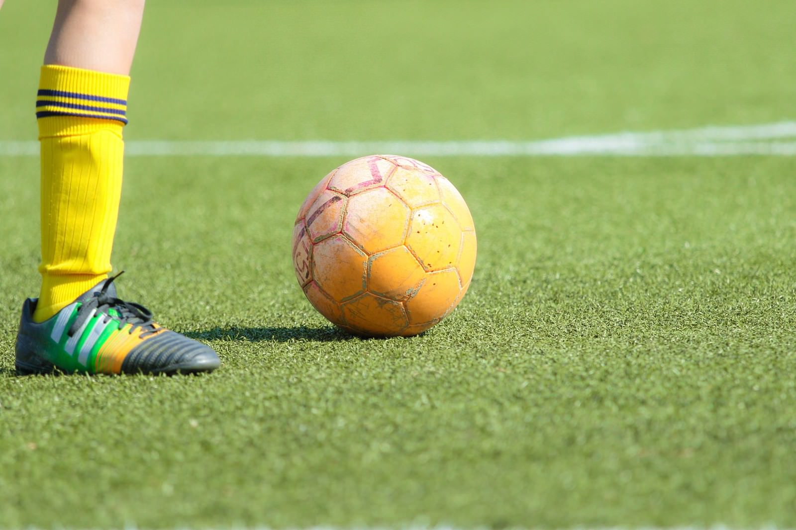 グラウンドのサッカーボールと選手の足元