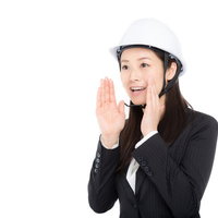 白いヘルメットをかぶり両手で声を出す女性の写真