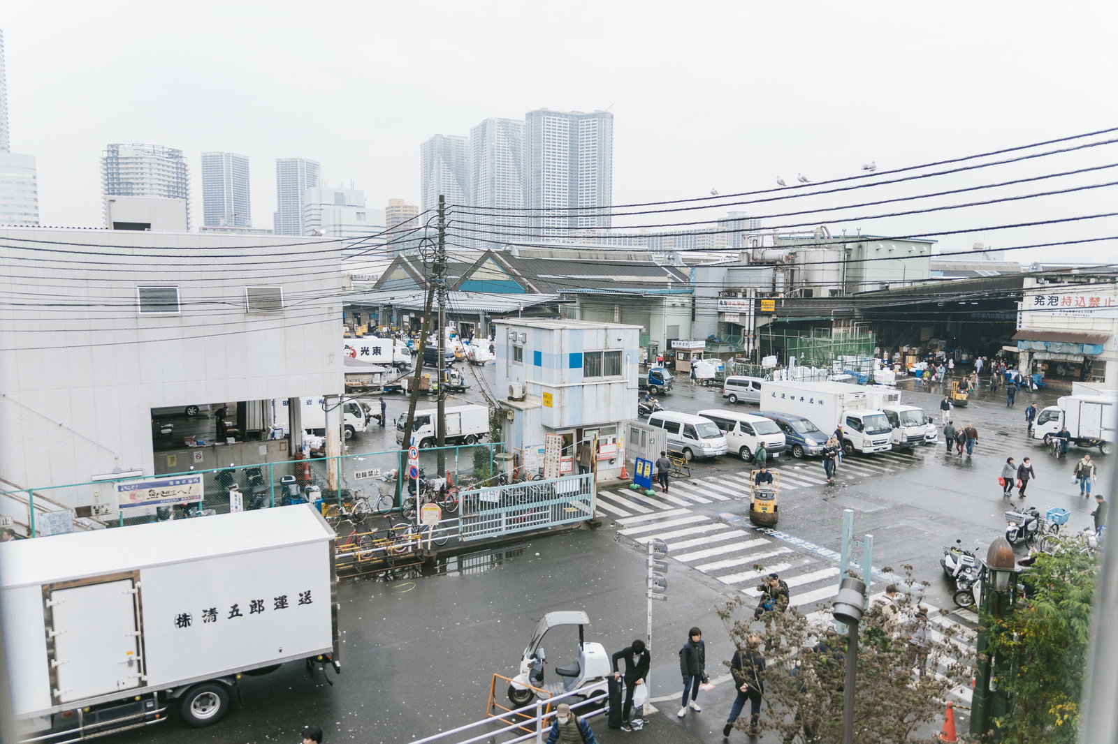 築地市場の入り口で行き交う人々と配送車が並ぶ風景