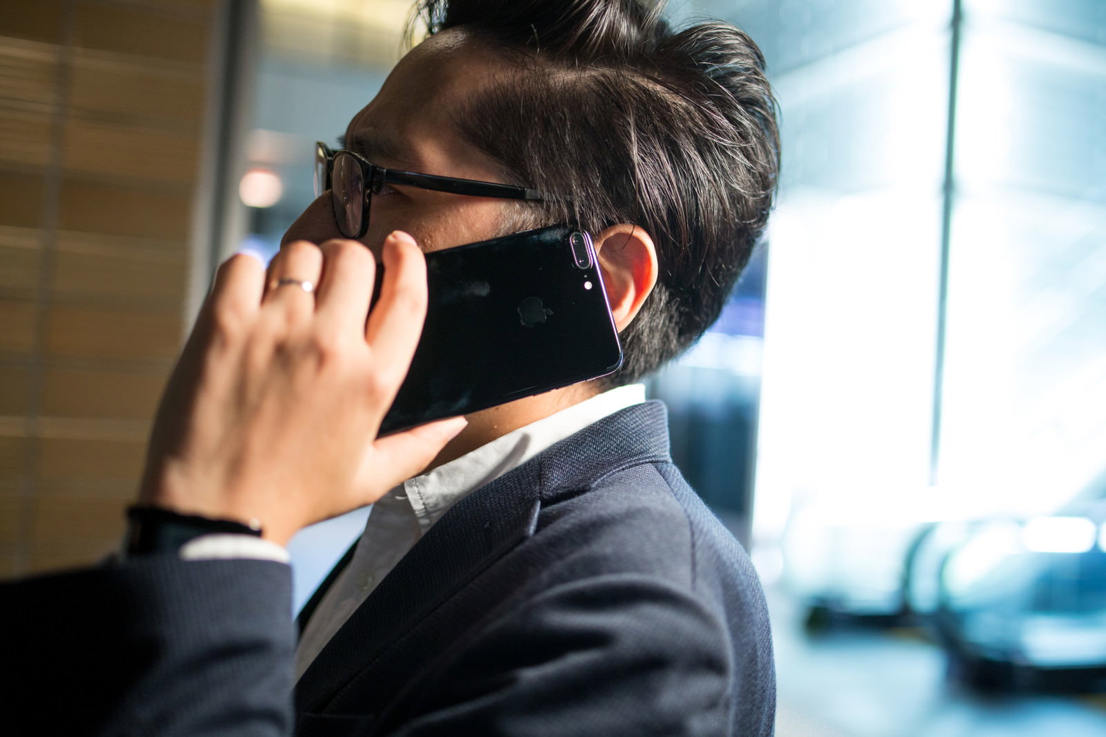 スマートフォンで通話しながら歩くサングラス姿のサラリーマン男性［モデル：ゆうせい］