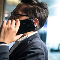 歩きながらスマートフォンで通話する重役ビジネスマンの写真