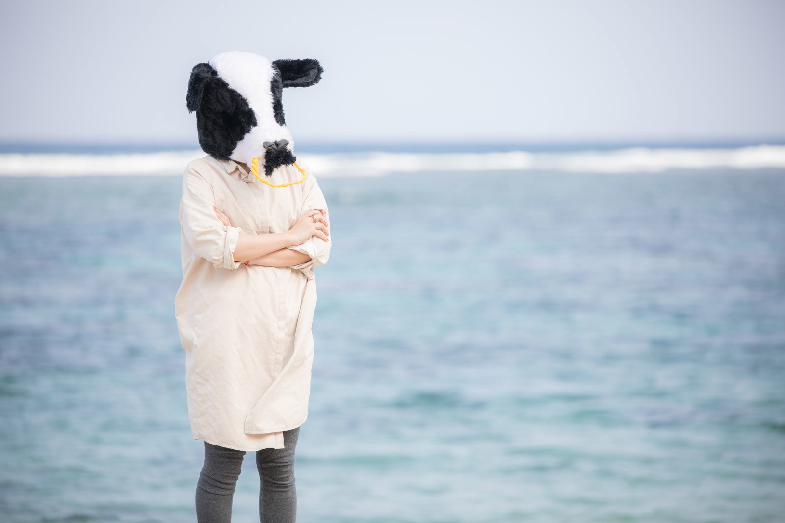海辺でベージュのコートを着て考え事をしている牛の角を持つ女性［モデル：古性のっち］