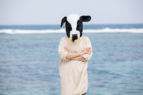 海を背に腕を組んで考える牛ガール