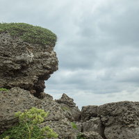 厚い雲に覆われた曇り空と岩場の風景の写真