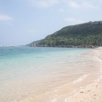 宮古島の白い砂浜と青いビーチ、透明な海と山々の景観の写真