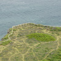 東平安名崎灯台からの景観、芝生に設置された木製ベンチと青い海の写真
