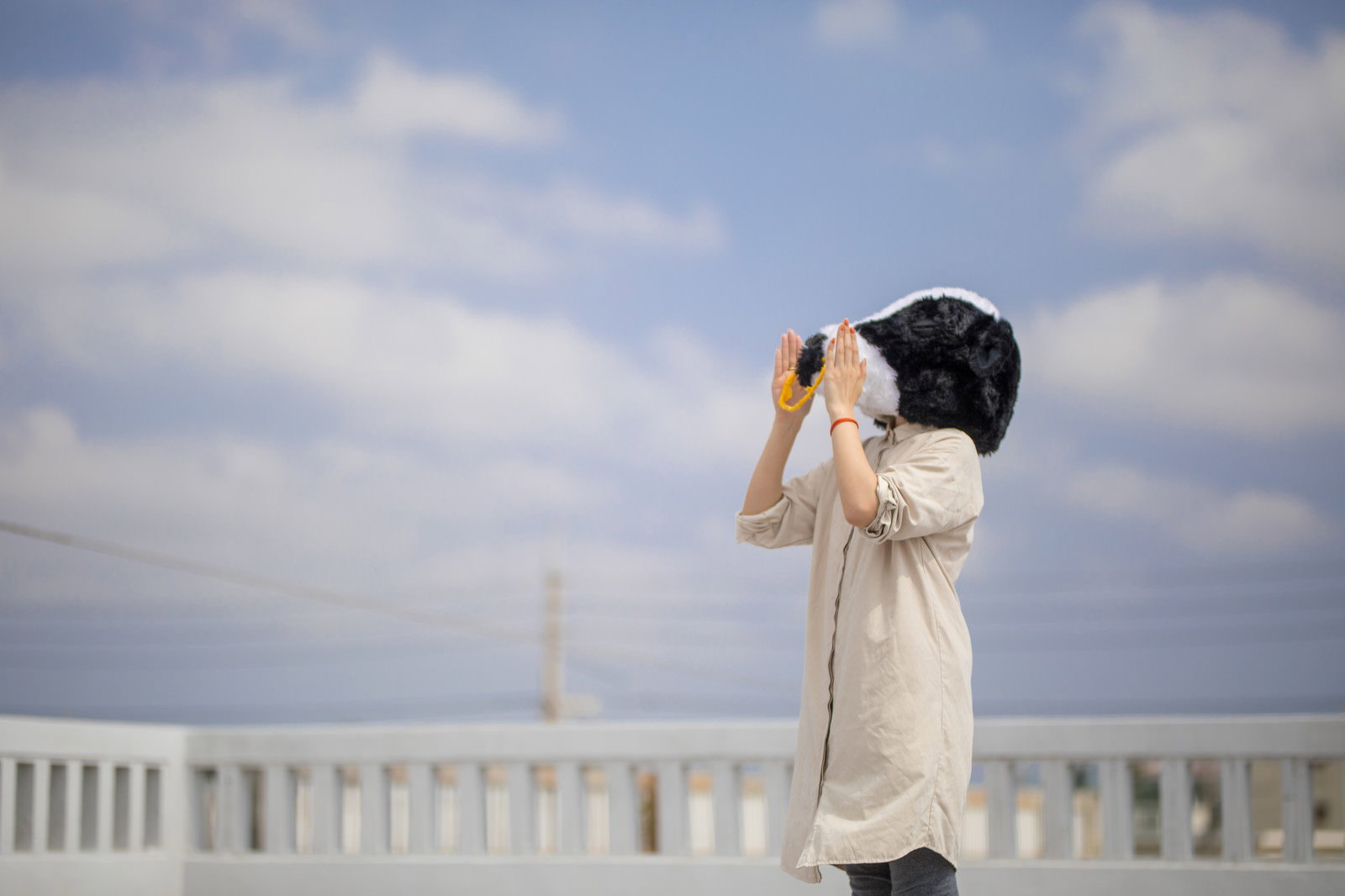 手を口元に当てて叫ぶ白いコートの女性［モデル：古性のっち］
