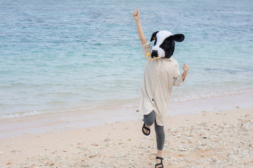 宮古島の砂浜で元気いっぱいの牛ガール、笑顔でポーズ