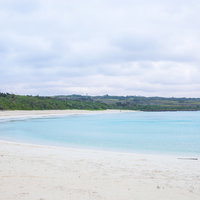 宮古島の白い砂浜と宮古ブルーの海（曇り空）の写真