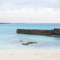 透明度の高い宮古ブルーの海と防波堤が見える宮古島の海岸の写真