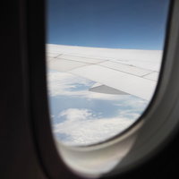 飛行機の窓から見える青空と雲海の景色の写真