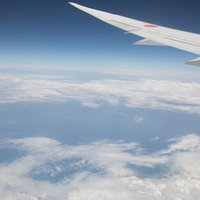 旅客機の翼と上空から見える雲海の景色 雲の層と青空の写真