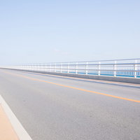 どこまでも続く伊良部大橋の道路と青い海空の写真