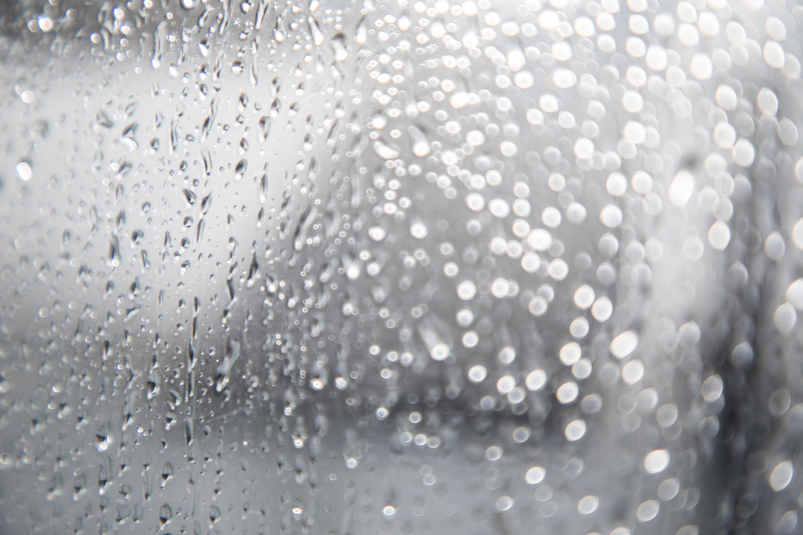 窓ガラスに付着した透明な雨の水滴がクローズアップされた写真