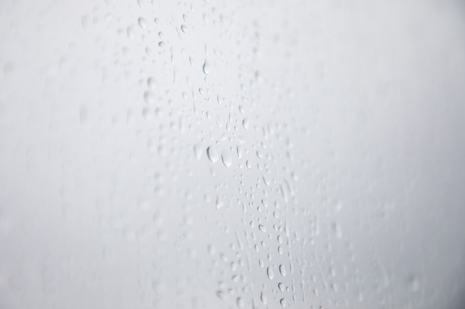 透明なガラス窓に無数の雨粒や水滴が付着している様子