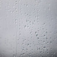 窓ガラスについた雨の水滴と梅雨の風景の写真