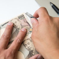 1万円札と同じ大きさに紙をカットする手作業の写真