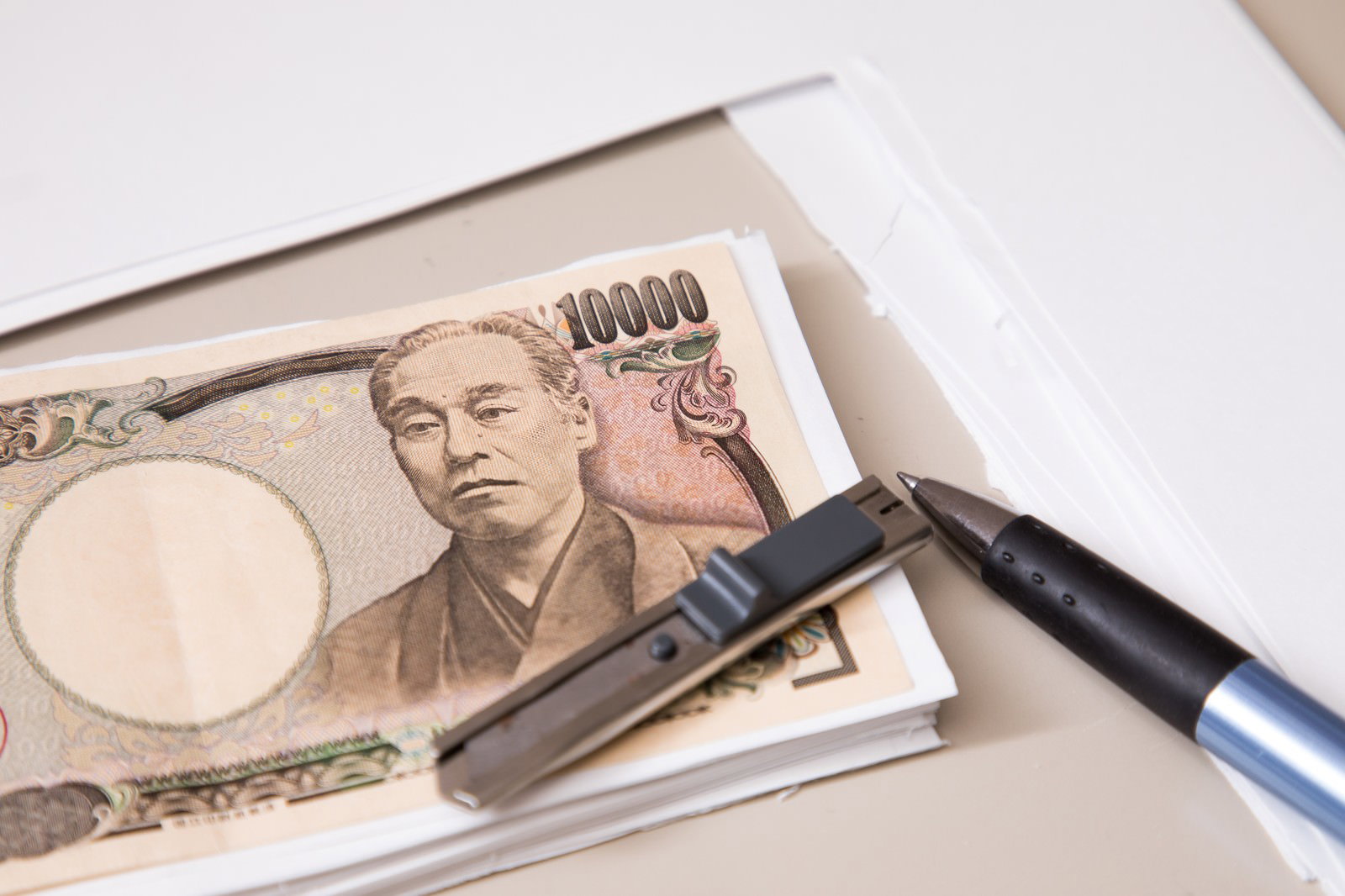 カッティングマットの上に置かれた一万円札とカッター