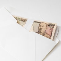 白い封筒から1万円札が覗く紙幣と現金、札束のお金の写真
