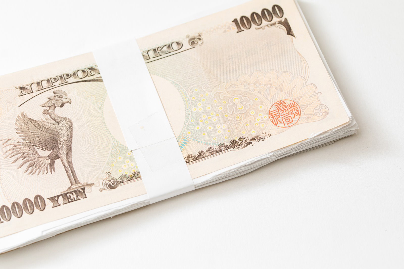 白い背景に置かれた一万円札の札束
