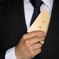 給与を内ポケットにしまうビジネスマンの様子の写真