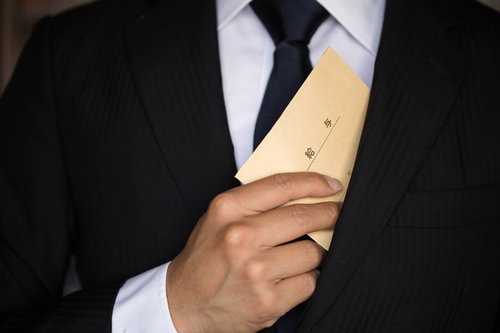 給与を内ポケットにしまうビジネスマンの様子