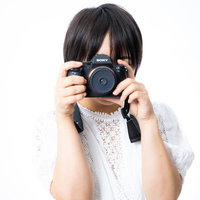 ファインダーを覗いてカメラを向ける女性フォトグラファーの写真