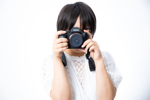 ファインダーを覗いてカメラを向ける女性フォトグラファー