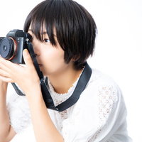 ファインダーを覗きながら構図を決める女子カメラマンの写真