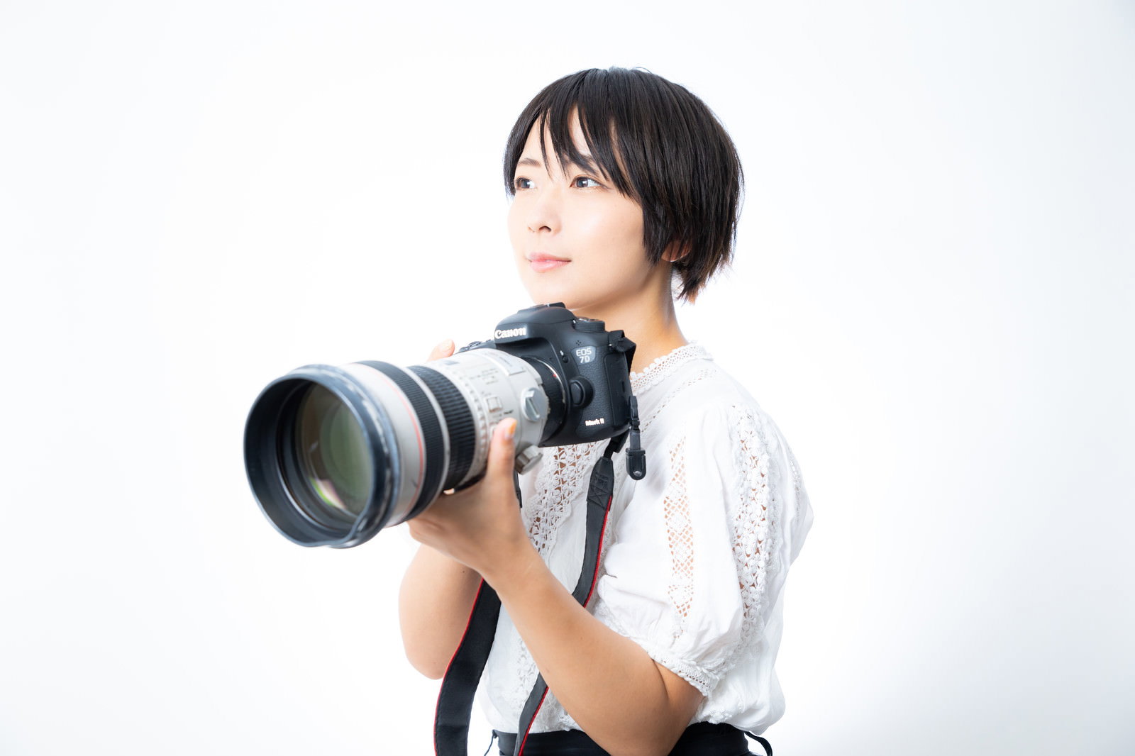 白い望遠レンズ付きの一眼レフカメラを構える女性［モデル：にゃるる］