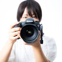 大口径のレンズで撮影中の女性フォトグラファーの写真