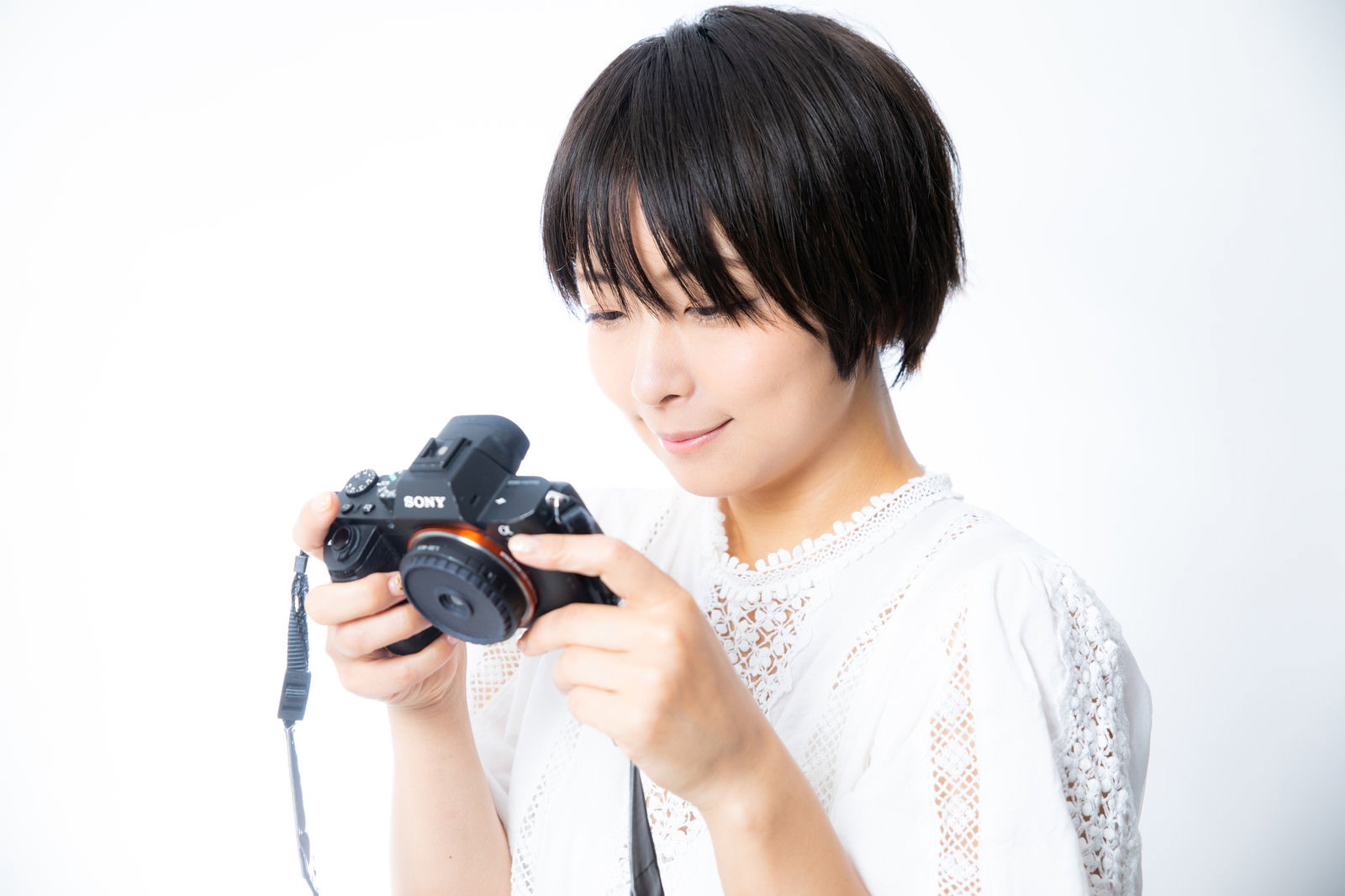 ミラーレスカメラを持って笑顔を見せるカメラ女子［モデル：にゃるる］