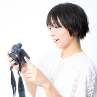撮影したミラーレスカメラの写真を嬉しそうに眺めるカメラ女子の写真