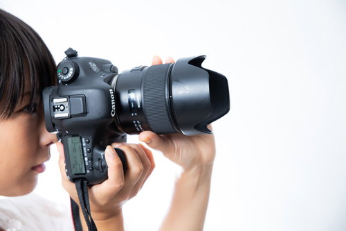 ファインダーを覗きながら縦位置で撮影するカメラ女子