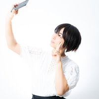 スマートフォンを掲げて俯瞰自撮りする女性の写真