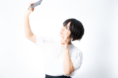 スマートフォンを掲げて俯瞰自撮りする女性