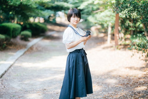 フォトウォーク中に振り返る公園でのカメラ女子