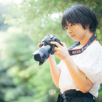 木漏れ日の中でカメラの設定を見直すカメラ女子の写真