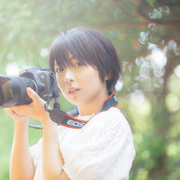木漏れ日の中で一眼レフを持ったカメラ女子の写真