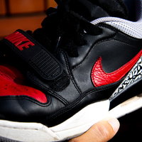 黒と赤のNIKEスニーカーをレンガ背景に手に持つの写真