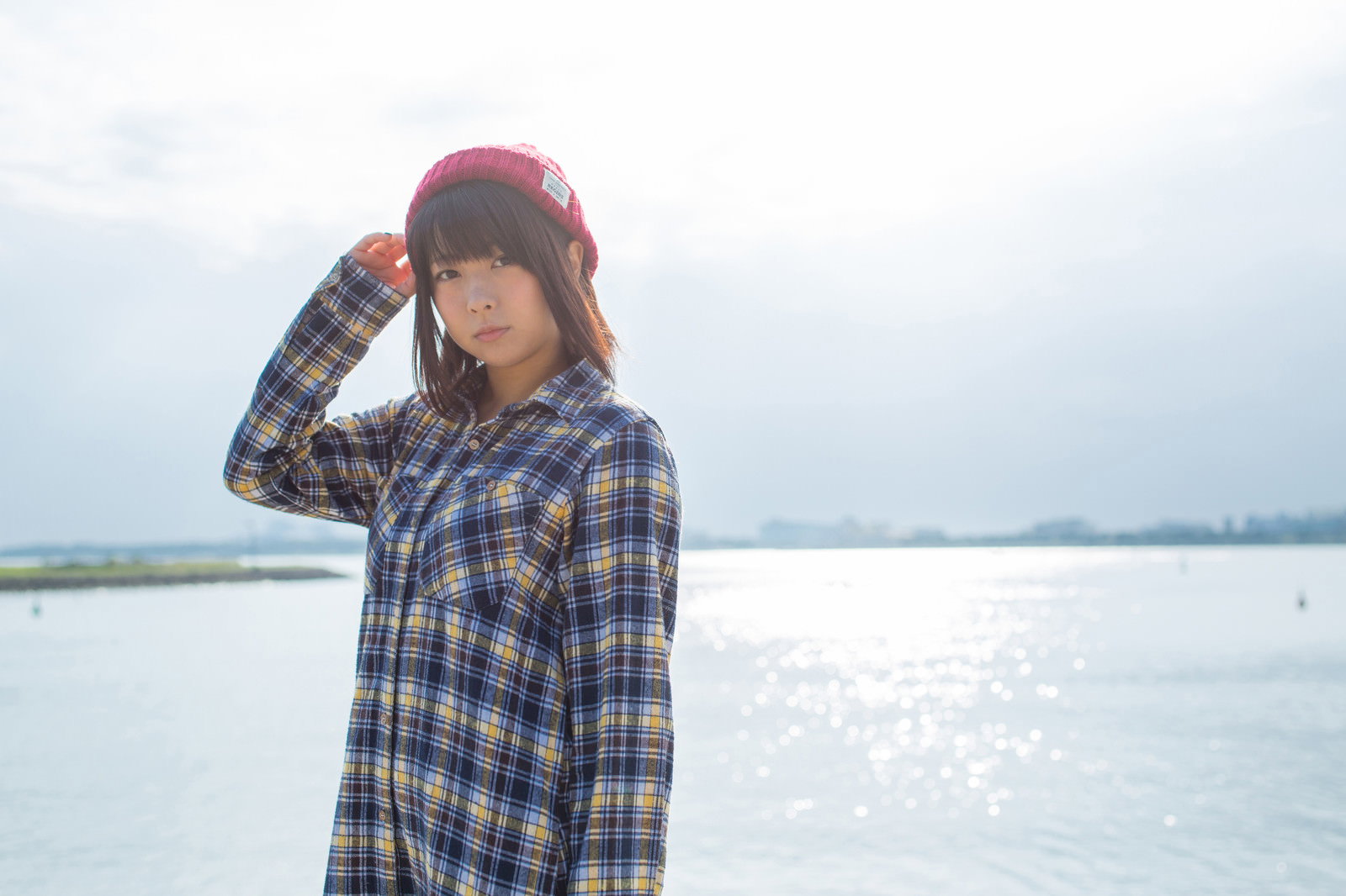 水辺でニット帽をかぶり立つ女性［モデル：にゃるる］