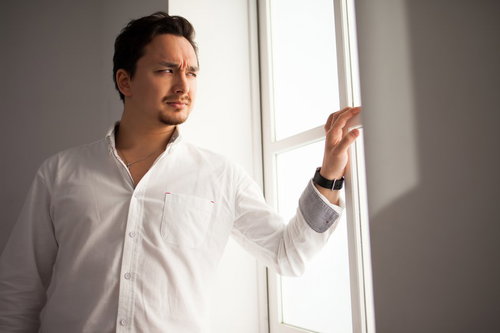 昨晩の記憶がない二日酔いのドイツ人ハーフ男性が窓辺で険しい表情