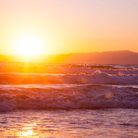 荒波と日の出の海辺風景 初日の出の朝焼けの写真