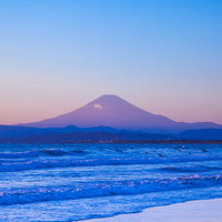 海でサーフィンするサーファーと富士山の絶景の写真