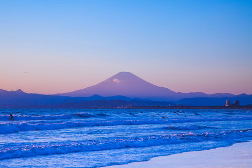 海でサーフィンするサーファーと富士山の絶景