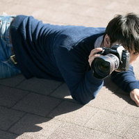 下心を抑えローアングルで撮影するアマチュアカメラマンの写真