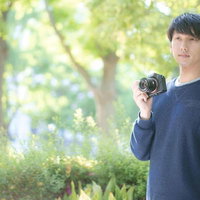 緑の中で一眼レフカメラを持つ散歩中のフォトグラファーの写真