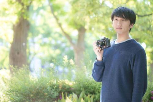 緑の中で一眼レフカメラを持つ散歩中のフォトグラファー